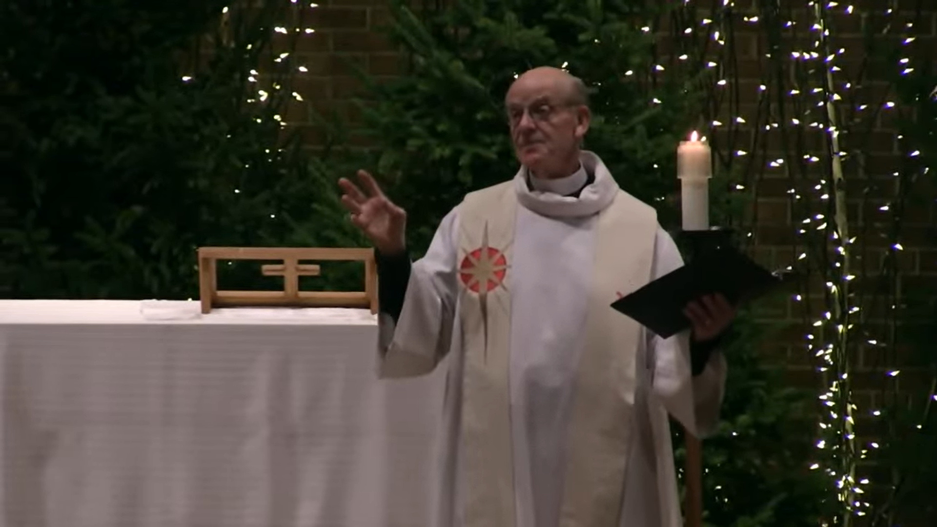 Pastor Glenn Seefeldt preaching at Nativity Lutheran Church with lit trees in the background