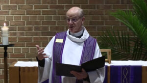 Pastor Glenn Seefeldt preaching at Nativity Lutheran Church in the sanctuary with palms in the background for Palm Sunday