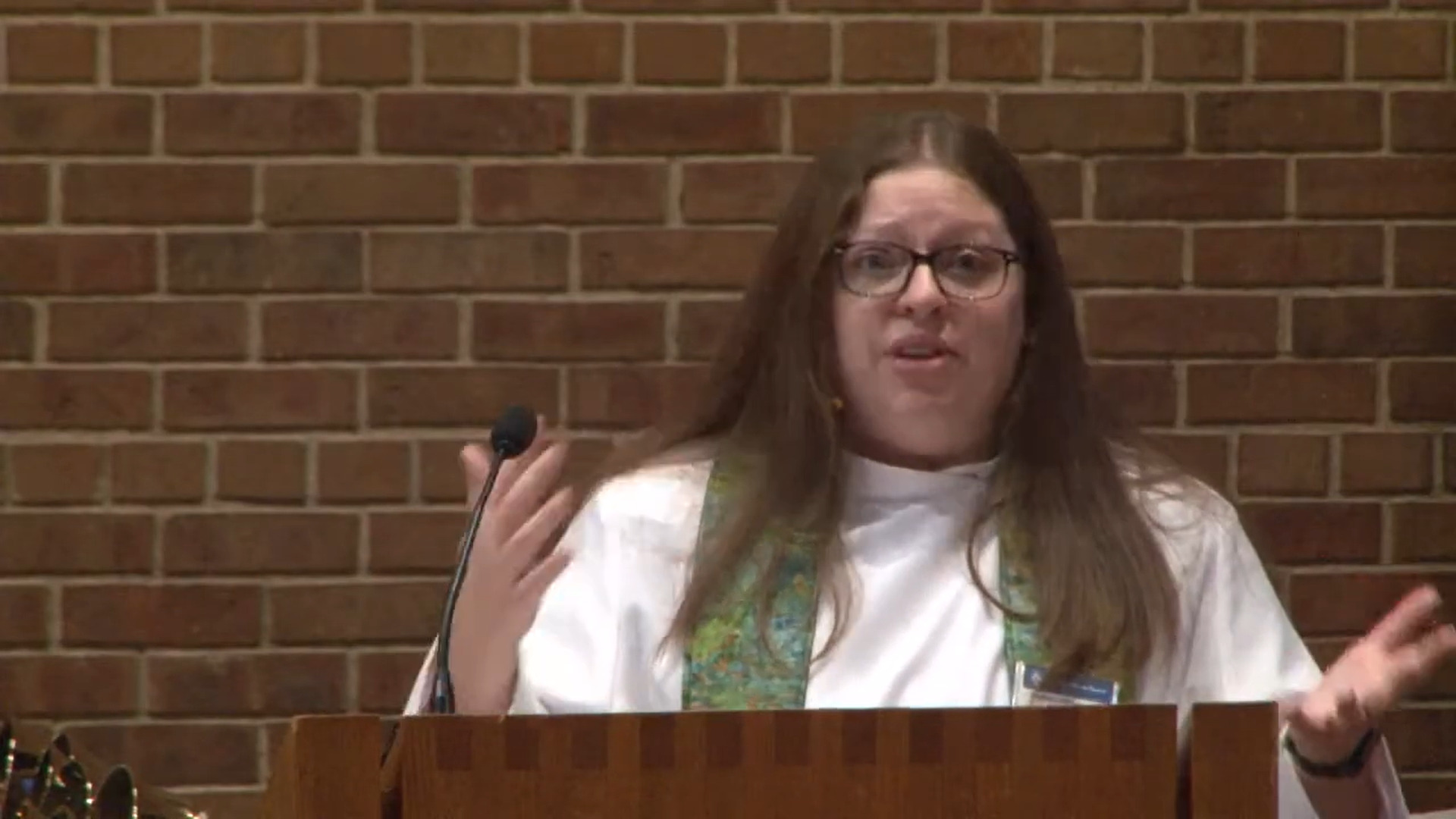 Pastor Angela LaMoore preaching in Nativity sanctuary against brick wall background