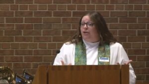 Pastor Angela LaMoore preaching in the Nativity sanctuary against a brick background